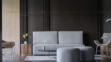 Ein modernes Wohnzimmer mit grauem Sofa, einem runden Couchtisch und einem Korbstuhl.