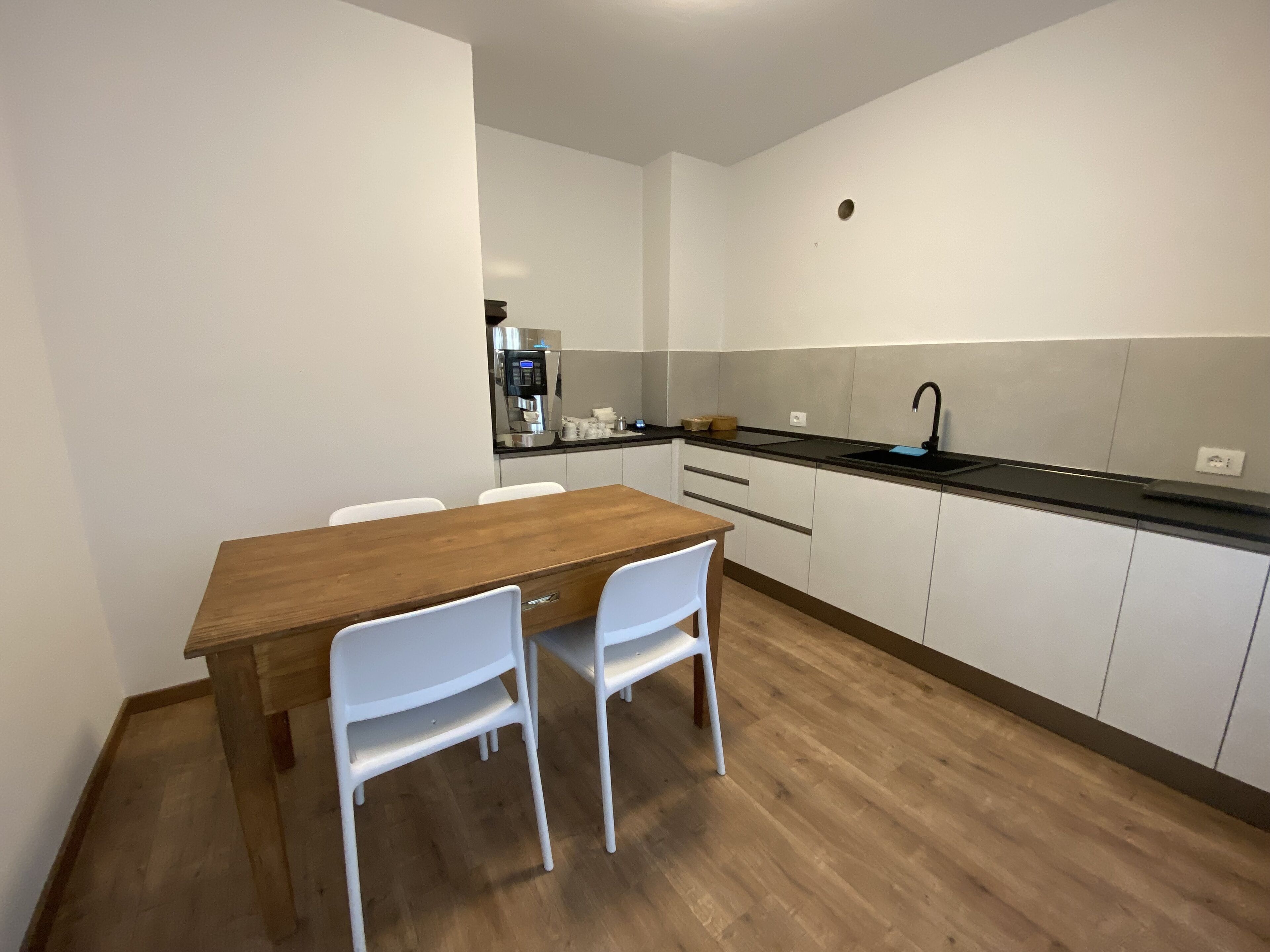 Eine moderne Küche mit weißen Schränken, einem Holztisch und zwei weißen Stühlen.