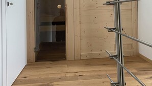 Una habitación con suelo de madera, tragaluz y barandilla de metal.