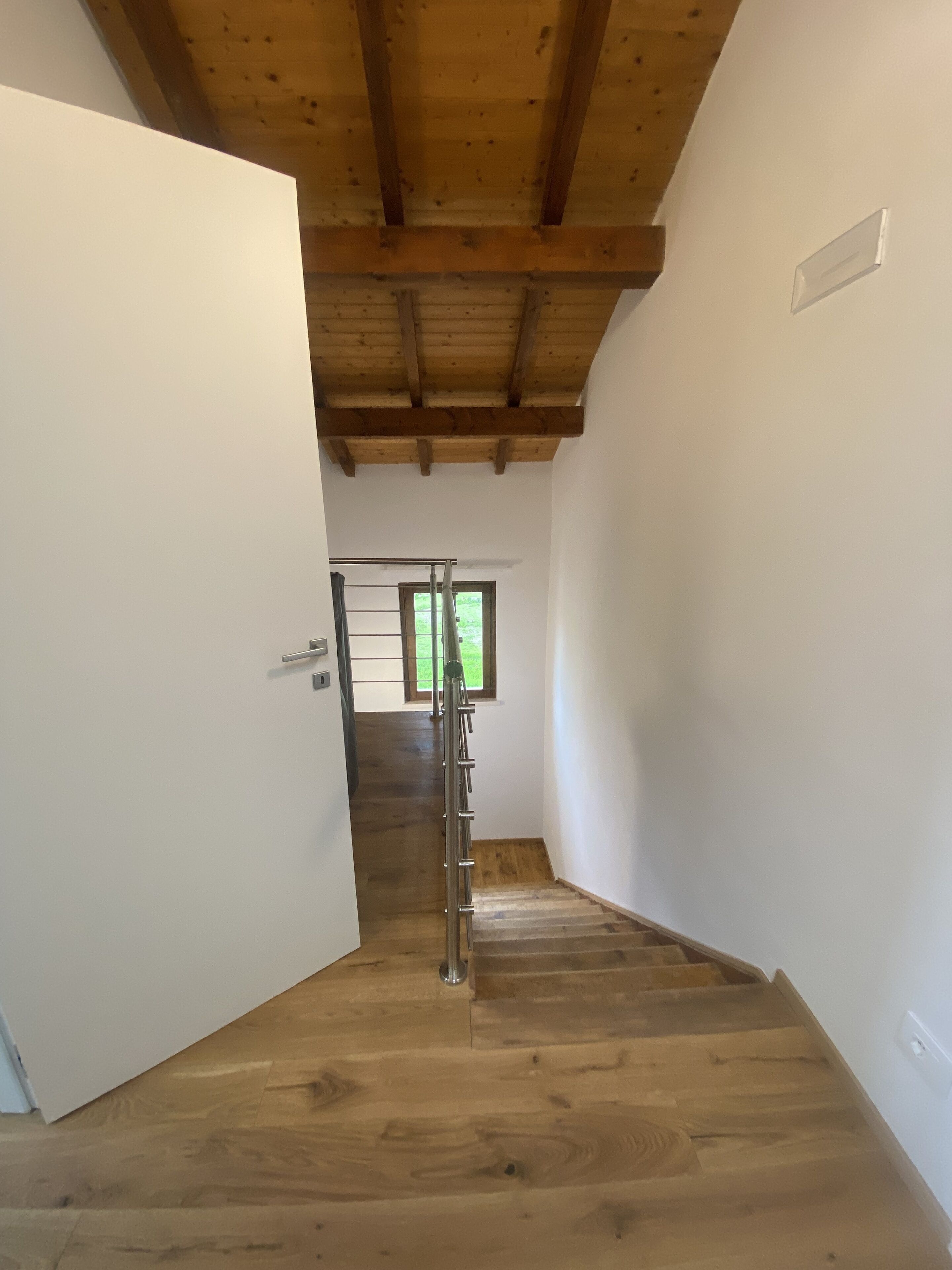 Una escalera de madera que sube a un segundo piso, con barandilla de metal.