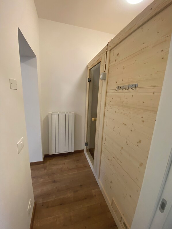A narrow hallway with wooden flooring, a white radiator, and a wooden door with a handle. - Vera Park & Wellness (Belluno)