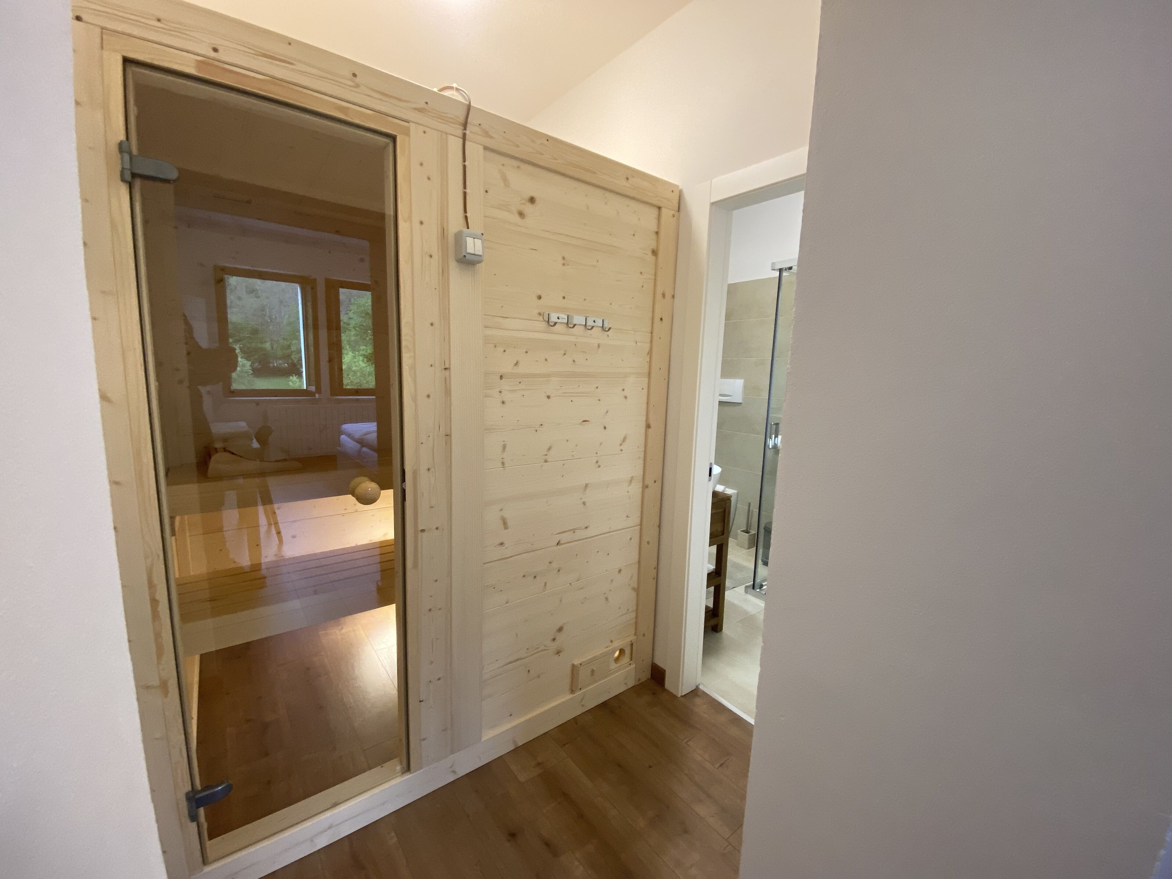 A wooden door leading to a bedroom with a bed and a window.