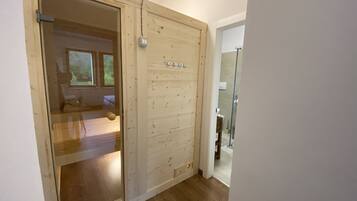 A wooden door leading to a bedroom with a bed and a window.