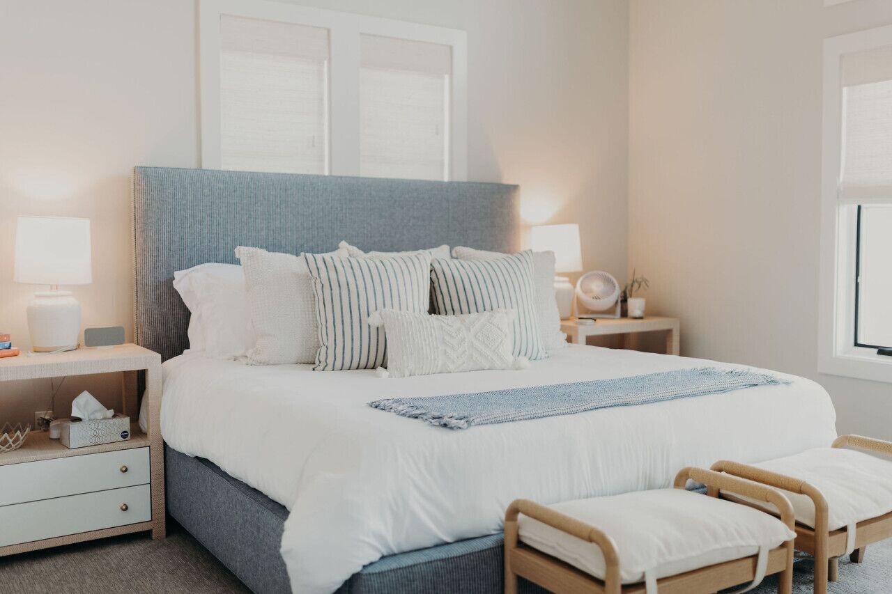 A neatly arranged bedroom with a large bed, bedside tables, and a window.