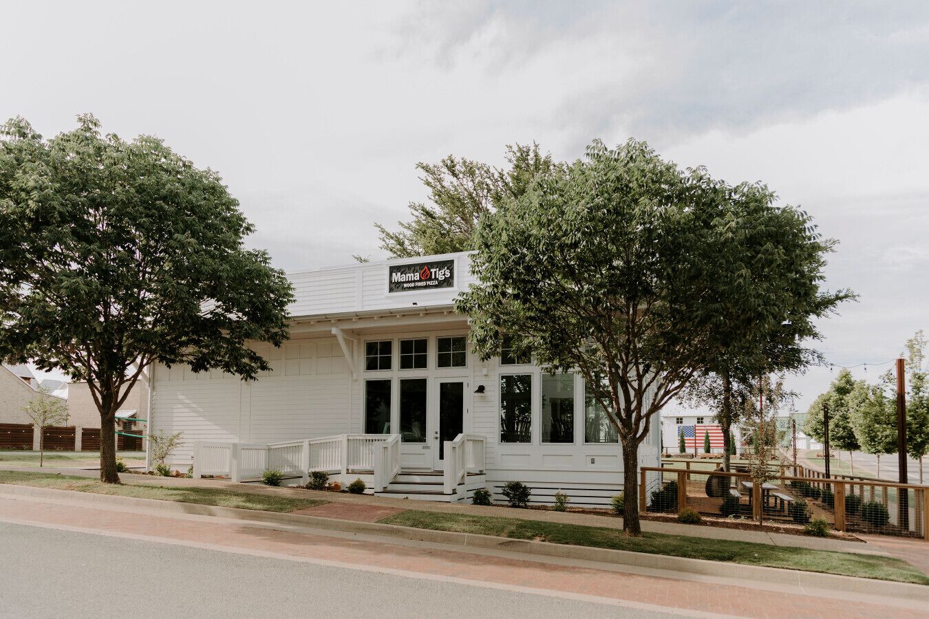 A white building with a sign reading "Mama Tig's Wood Fired Pizza."