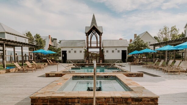 A pool area with multiple pools, lounge chairs, and umbrellas.