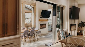 A modern living room with a dining area, a fireplace, and a TV mounted on the wall. - Crew`s Cottage|Carlton Landing|Fire Pit|Screened Porch|Outdoor Fireplace (Carlton Landing)