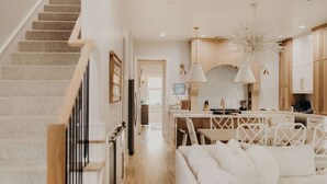 A modern kitchen with a central island, white cabinetry, and a staircase leading to another level.