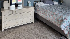 Une chambre à coucher avec un lit, une commode et une fenêtre donnant sur un beau paysage.