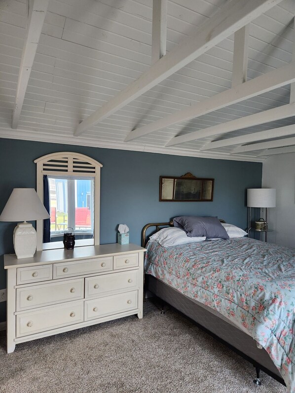 A bedroom with a bed, dresser, and a window with a view.