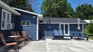 Une maison bleue dotée d’un patio aménagé avec du mobilier d’extérieur et un espace salon abrité.