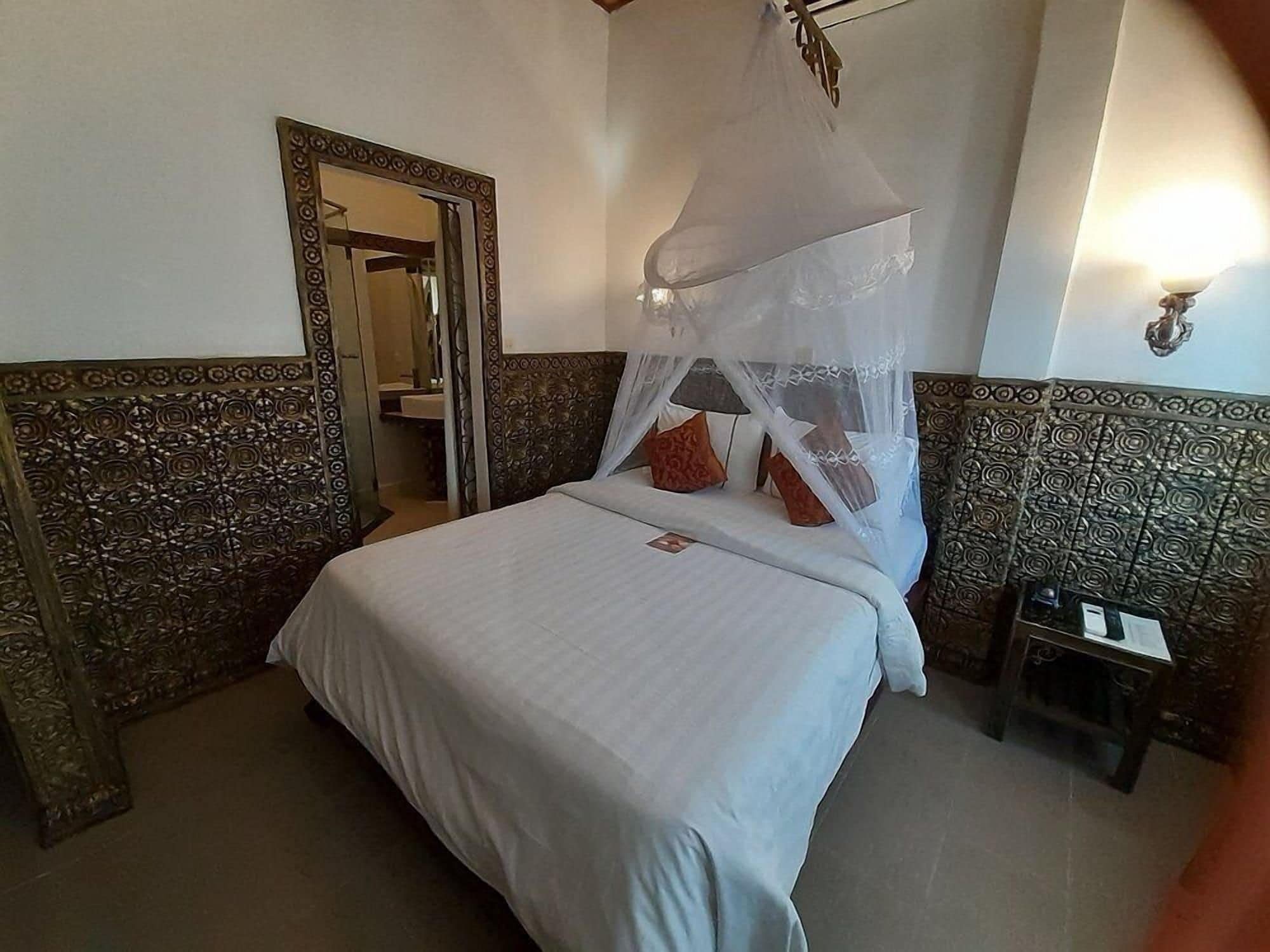 Una cama con dosel, un espejo y una pared con paneles decorativos.