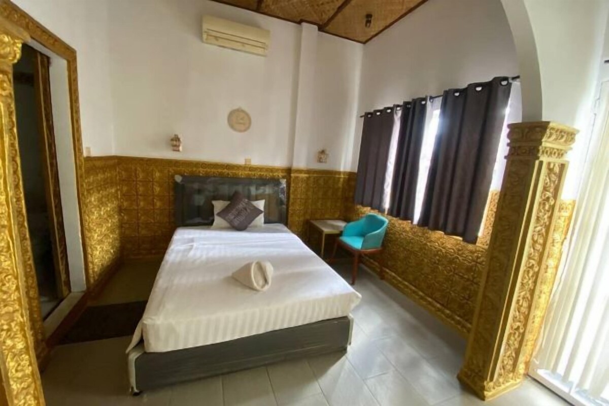 Una camera d'albergo con un letto, un tavolino, una sedia e una finestra con tende.