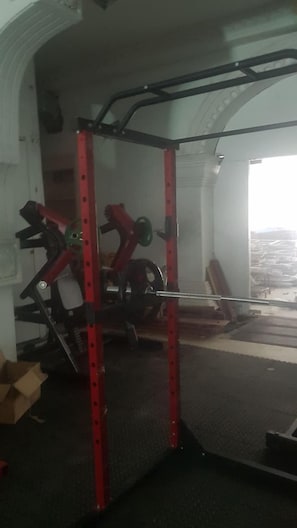 A gym with a red squat rack and weight plates. - Le Hotel Hotel (Phnom Penh)
