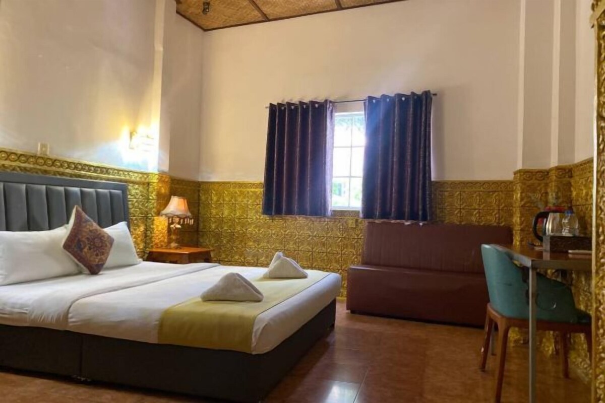 Una camera d'albergo con un letto, una scrivania, una sedia e una finestra con tende.