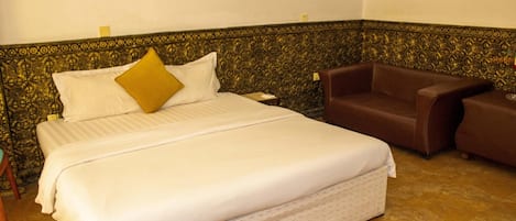 Una habitación de hotel con una cama grande, un sofá marrón y una pared con estampado.