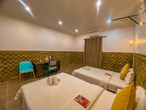 Una camera d'albergo con due letti, una scrivania con una sedia e un minibar.