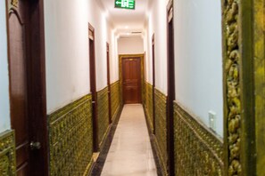 Un pasillo con suelo de mármol, puertas de madera y paredes con estampado verde.