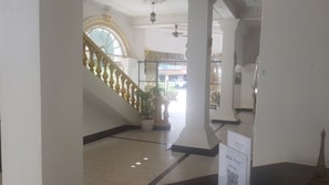 A grand staircase with ornate balustrades, leading to a balcony with a view of the street. - Le Hotel Hotel (Phnom Penh)