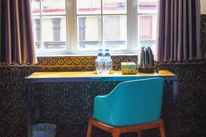 A room with a window, a table with a kettle, bottles, and a box. - Le Hotel Hotel (Phnom Penh)