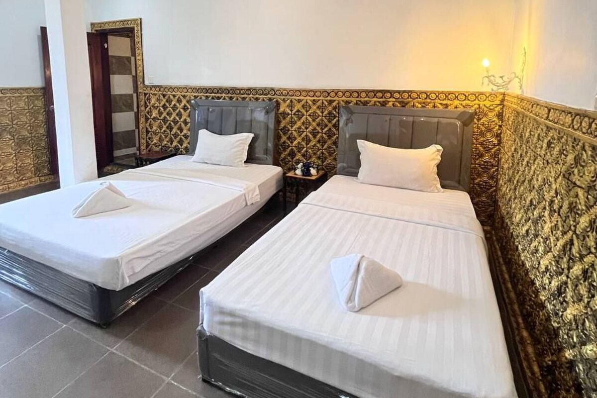 Een hotelkamer met twee bedden, een spiegel en wanden met een patroon.