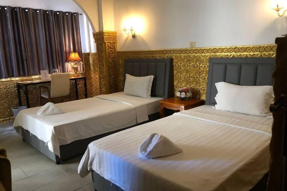 Una camera d'albergo con due letti, una scrivania, una sedia e una lampada.