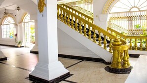 Een statige trap met gouden balustrades en witte kolommen in een ruime ruimte.