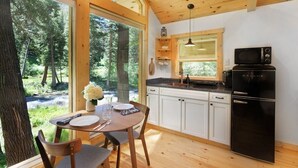 A modern kitchen with white cabinets, a black refrigerator, and a window overlooking a forest. - Creekside Maroon Bells Cabin at T-Lazy-7 Ranch, 5 Min to Maroon Bells & Highlands, 10 to Aspen (Aspen)