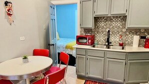 A compact kitchen with grey cabinets, a red microwave, and a small sink.