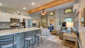A modern kitchen with a large island, bar stools, and a dining area with a sofa and coffee table. - Lakefront Osceola Vacation Rental - Dogs Welcome! (Osceola)