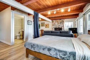 A spacious bedroom with a large bed, a stone fireplace, a television, and a wooden ceiling. - Lakefront Osceola Vacation Rental - Dogs Welcome! (Osceola)