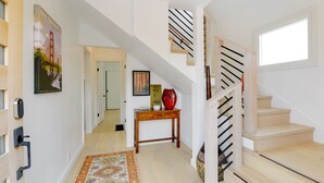 A staircase with a wooden finish and black railings, a patterned rug on the floor, and a door with a key lock. - Pet-Friendly El Cerrito Home: Deck, Sauna & Views! (El Cerrito)
