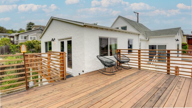 A white house with a wooden deck and two rocking chairs. - Pet-Friendly El Cerrito Home: Deck, Sauna & Views! (El Cerrito)