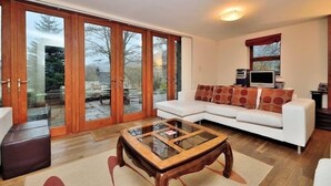 Een woonkamer met een witte bank, een glazen salontafel en een televisietoestel.