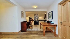 Een gang die uitkomt in een keuken met een eettafel en stoelen.
