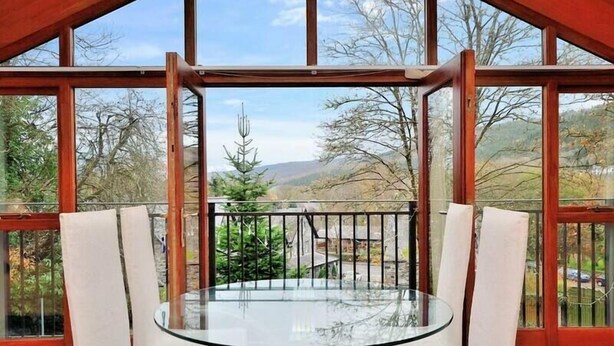 Een glazen tafel met witte stoelen in een kamer met grote ramen en een balkon.