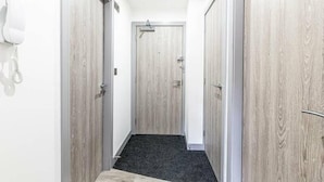A narrow hallway with wooden doors and a carpeted floor.