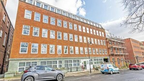 A multi-story building with a brick facade, large windows, and a flat roof.