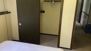 Ett hotellrum med en säng, en garderob och en klädställning.