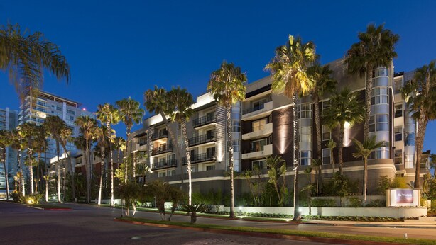 A multi-story hotel with balconies, palm trees, and a sign indicating 'The Westbury'.