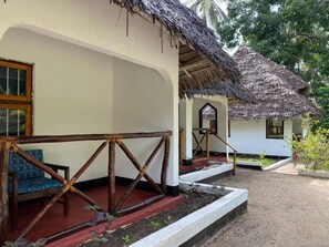 A bungalow with a thatched roof, a wooden porch, and a red carpet leading to the entrance. - Unguja Ukuu Kaepwani (Unguja Ukuu)