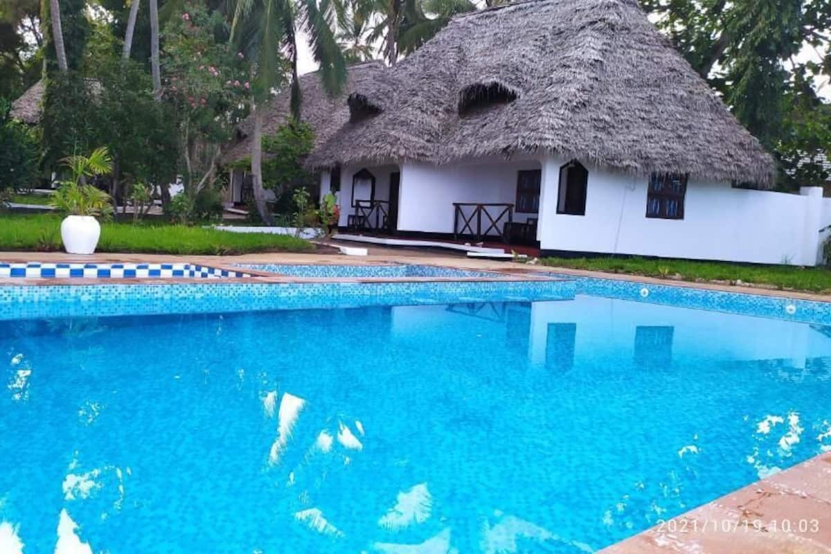 Une piscine avec une structure au toit de chaume en arrière-plan.