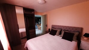 Une chambre avec un grand lit, une armoire et un bureau avec une lampe.