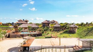 Un resort con cabañas de techo de paja, una piscina y un césped bien cuidado.