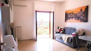 En moderne stue med sofa, spisebord og stort vindue med udsigt over bybilledet.