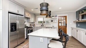 Una cocina moderna con electrodomésticos de acero inoxidable, una isla grande e iluminación colgante.