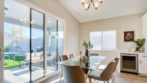 A modern kitchen with a glass dining area, sliding glass doors to a patio, and a chandelier.
