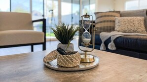 A wooden table with a woven basket, a small potted plant, and a vintage-style hourglass.