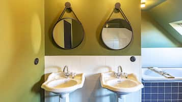 Une salle de bain avec deux lavabos, deux miroirs et une baignoire.