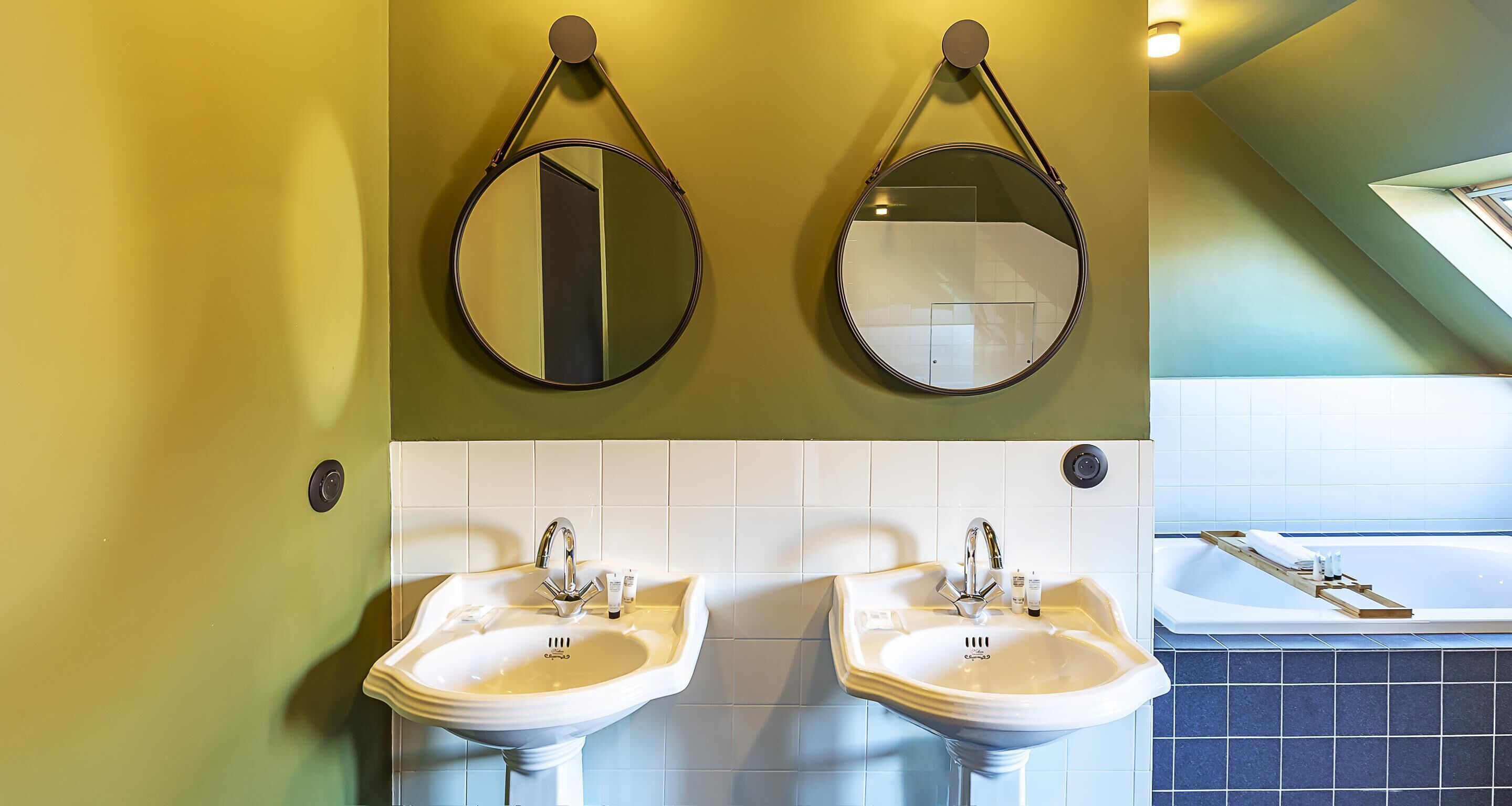 A bathroom with two sinks, two mirrors, and a bathtub.